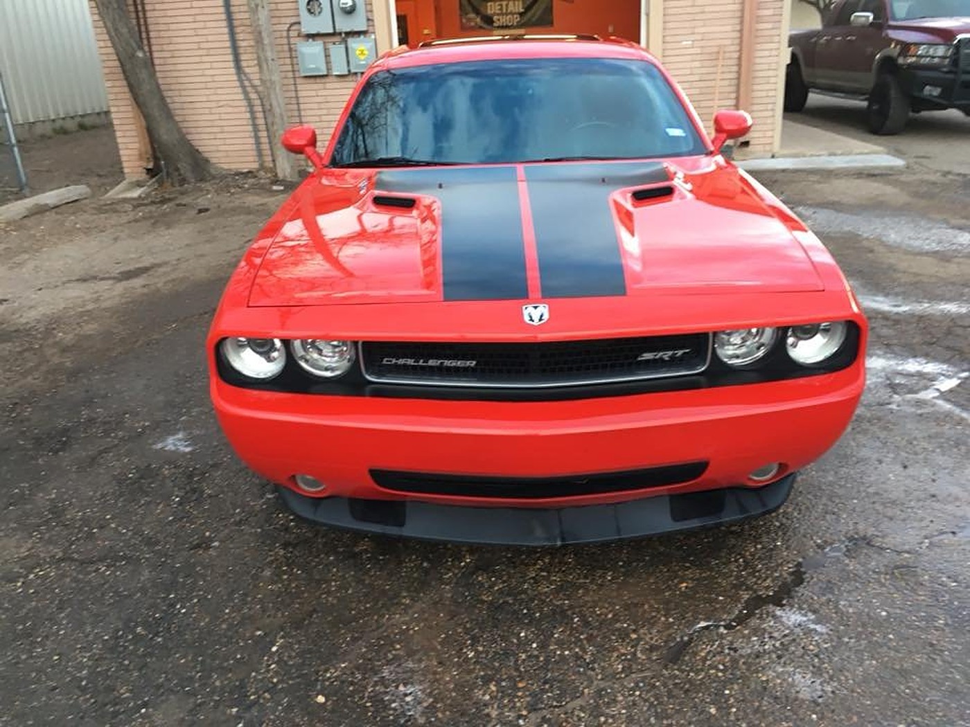 Red Dodge Challenger SRT freshly detailed in front of AJ's Auto Rehab shop